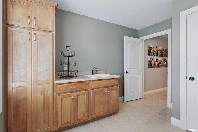 bathroom featuring a sink, tile patterned floors, and baseboards