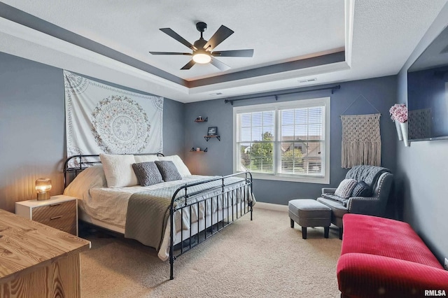 bedroom with a tray ceiling, carpet, baseboards, and a ceiling fan