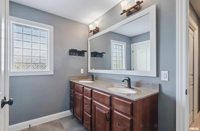 bathroom featuring tile patterned floors, baseboards, and double vanity