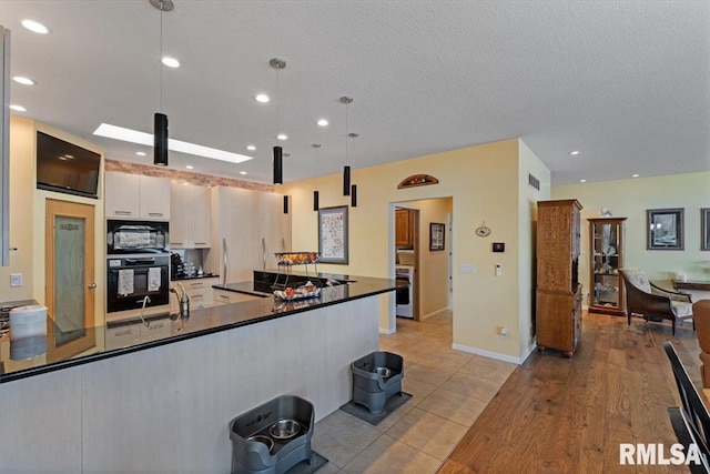kitchen with black appliances, dark countertops, white cabinets, pendant lighting, and recessed lighting