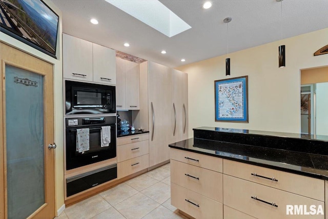 kitchen featuring black appliances, a skylight, a warming drawer, light tile patterned floors, and dark stone counters