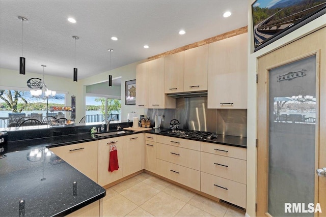 kitchen featuring a sink, under cabinet range hood, stainless steel gas cooktop, hanging light fixtures, and recessed lighting