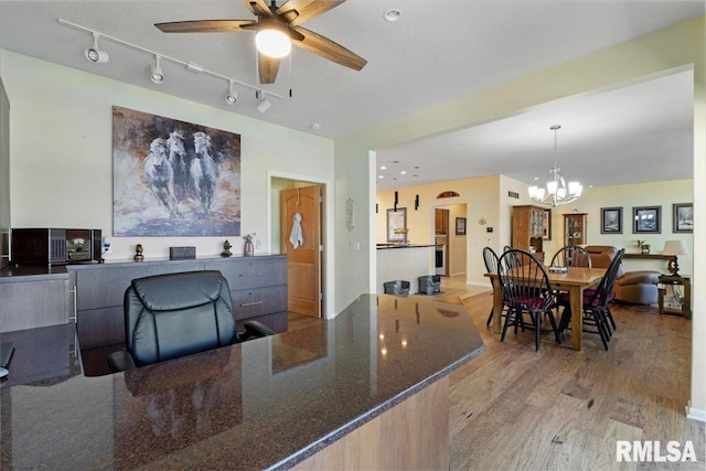 home office featuring wood finished floors, a chandelier, a ceiling fan, and track lighting