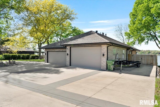 view of side of home with driveway, brick siding, fence, a garage, and a shingled roof