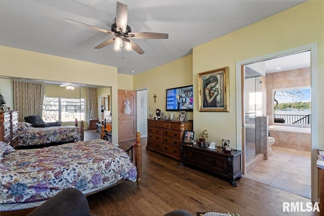 bedroom featuring multiple windows, wood finished floors, ensuite bath, and a closet