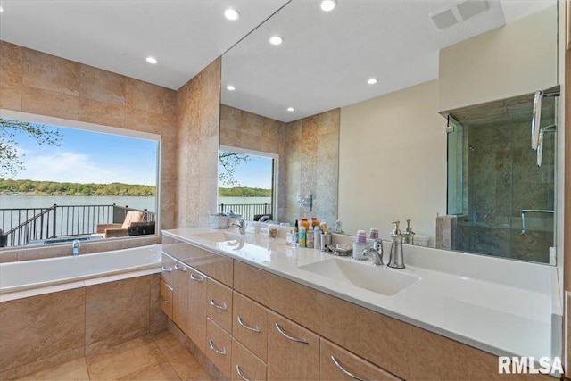 bathroom featuring recessed lighting, a bath, a stall shower, double vanity, and a water view