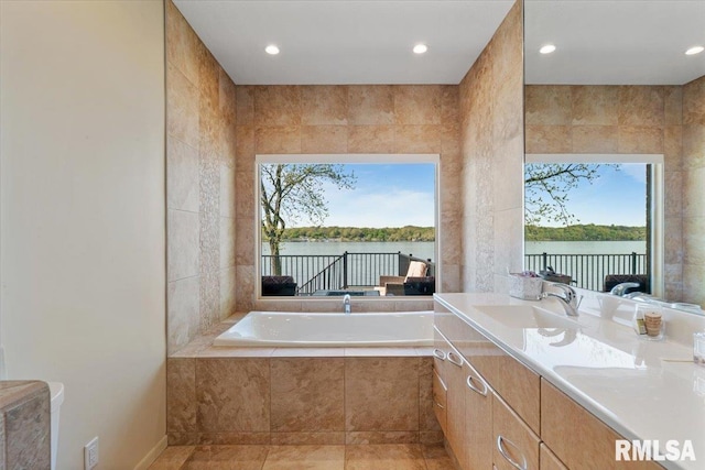 full bathroom with plenty of natural light, a bath, a water view, vanity, and recessed lighting