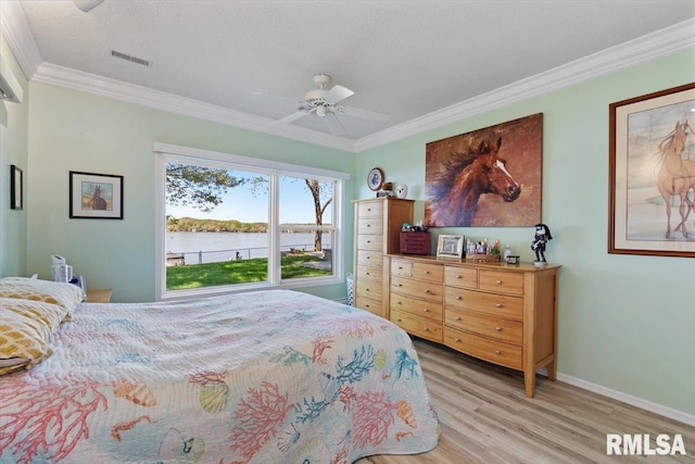 bedroom featuring light wood-type flooring, a water view, crown molding, baseboards, and ceiling fan