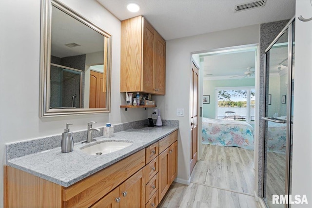full bathroom with wood finished floors, ensuite bath, a ceiling fan, a stall shower, and vanity