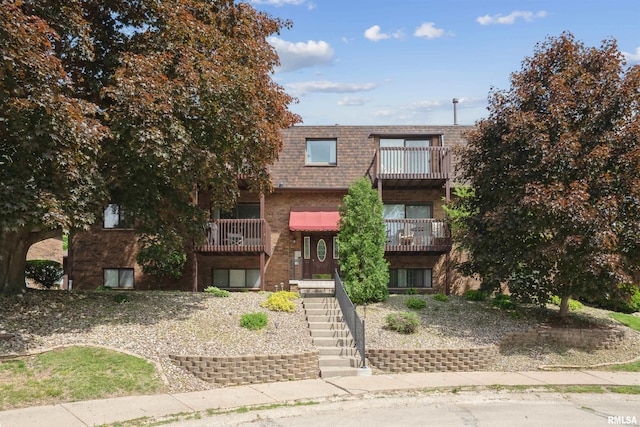 2505 26th Avenue Ct Unit J, Rock Island, IL 61201 - view of front of house featuring brick siding, stairway, mansard roof, a balcony, and roof with shingles