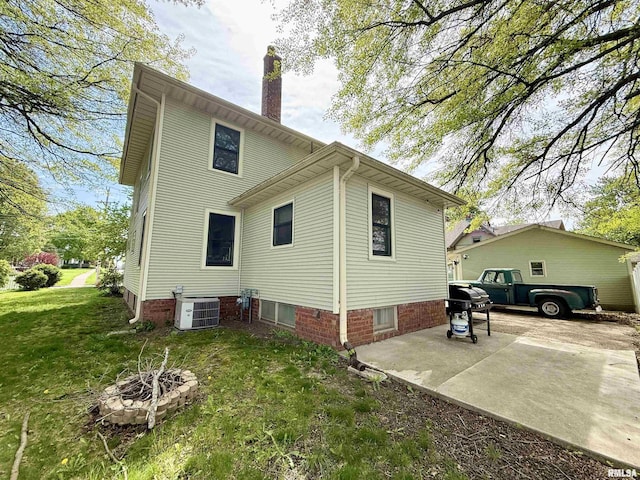 101 S Stewart St, Geneseo, IL 61254 - view of side of property featuring a yard, a chimney, central AC unit, an outdoor fire pit, and a patio area