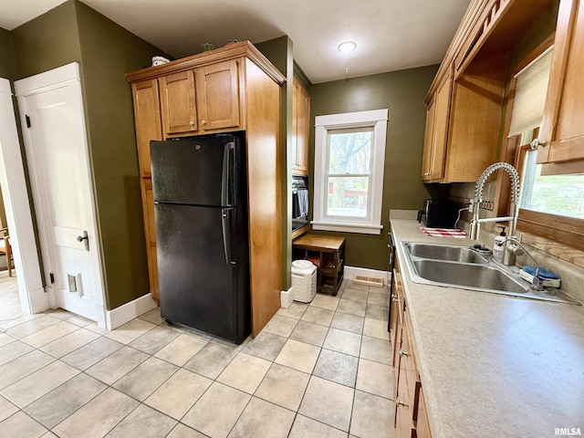 101 S Stewart St, Geneseo, IL 61254 - kitchen featuring freestanding refrigerator, a sink, baseboards, light tile patterned floors, and light countertops