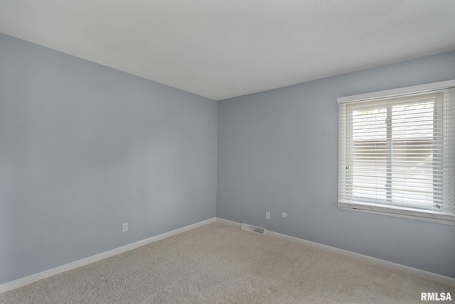 empty room featuring carpet and baseboards
