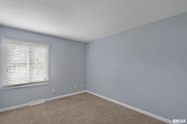 carpeted spare room featuring baseboards and a textured ceiling
