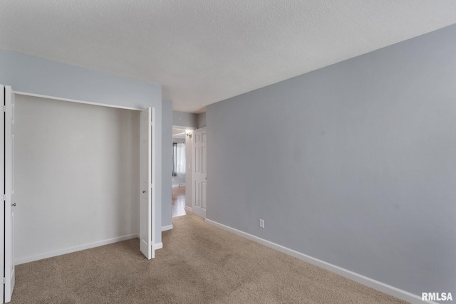unfurnished bedroom with carpet flooring, a closet, baseboards, and a textured ceiling