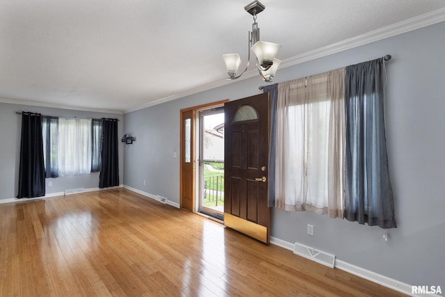 entrance foyer with a chandelier, ornamental molding, baseboards, and light wood finished floors