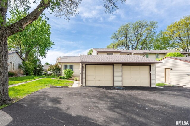 view of front of house featuring a shingled roof, a front lawn, driveway, and a garage