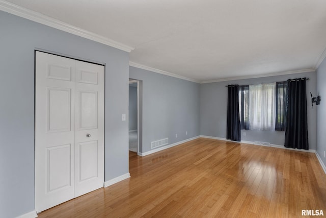 spare room with ornamental molding, light wood finished floors, and baseboards