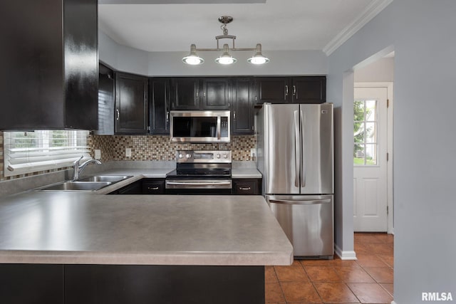 kitchen featuring stainless steel appliances, a sink, tasteful backsplash, tile patterned floors, and dark cabinetry