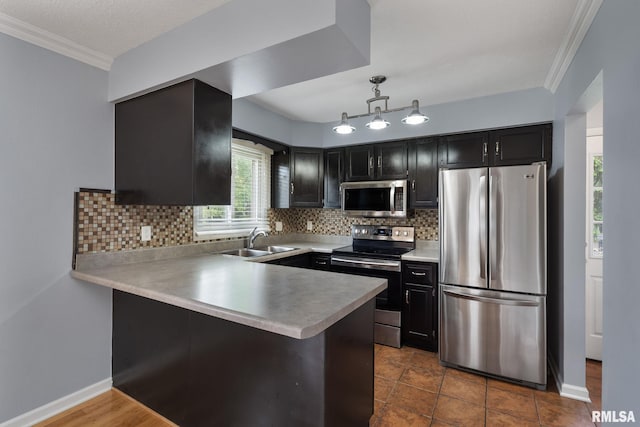 kitchen featuring stainless steel appliances, a sink, ornamental molding, dark cabinetry, and a peninsula