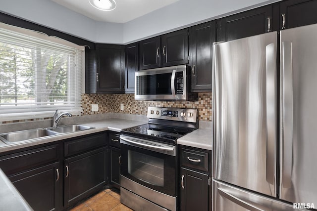 kitchen with appliances with stainless steel finishes, dark cabinets, a sink, and light countertops