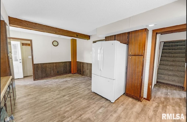 kitchen with freestanding refrigerator, light wood-style flooring, a wainscoted wall, beamed ceiling, and light countertops
