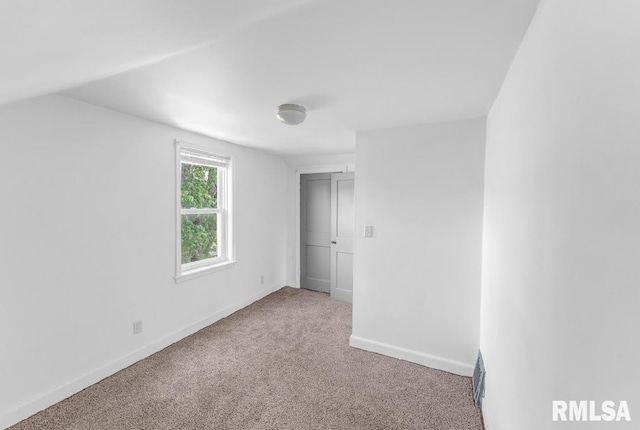 unfurnished bedroom with carpet flooring, baseboards, and vaulted ceiling