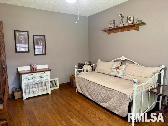 bedroom with wood finished floors, baseboards, and a textured ceiling