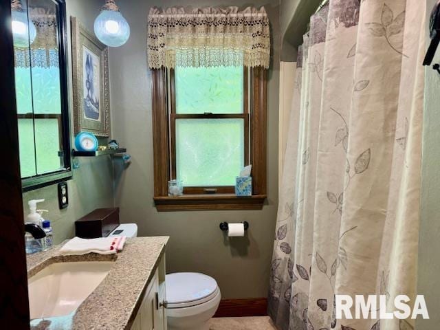 full bath featuring plenty of natural light, toilet, vanity, and baseboards