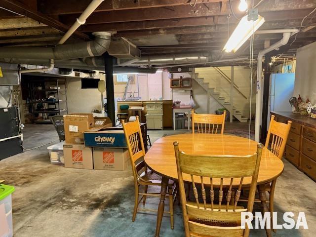 unfinished basement featuring stairs and freestanding refrigerator