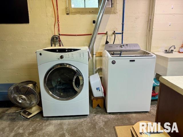 laundry room featuring washing machine and clothes dryer and concrete block wall