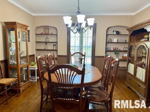 dining space with a chandelier, wood finished floors, built in shelves, and ornamental molding