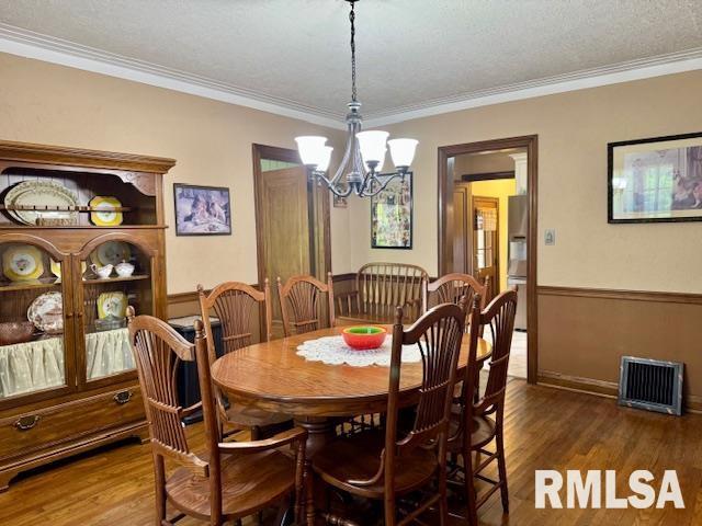 dining space featuring a chandelier, wood finished floors, crown molding, and baseboards