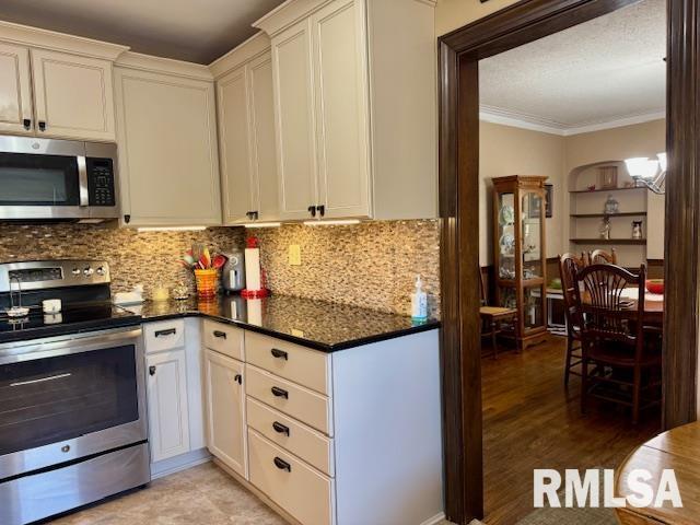 kitchen featuring appliances with stainless steel finishes, crown molding, backsplash, and white cabinetry