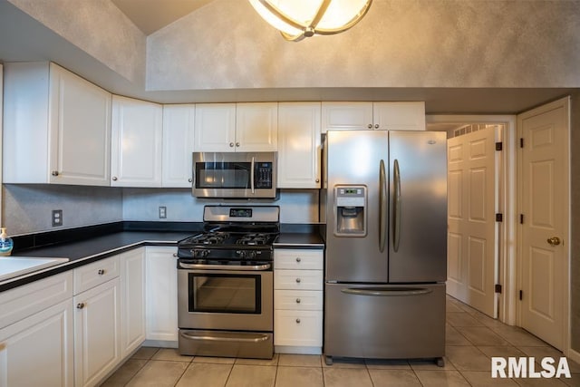 12 Old Marion Rd, West Frankfort, IL 62896 - kitchen featuring stainless steel appliances, light tile patterned flooring, dark countertops, white cabinets, and vaulted ceiling