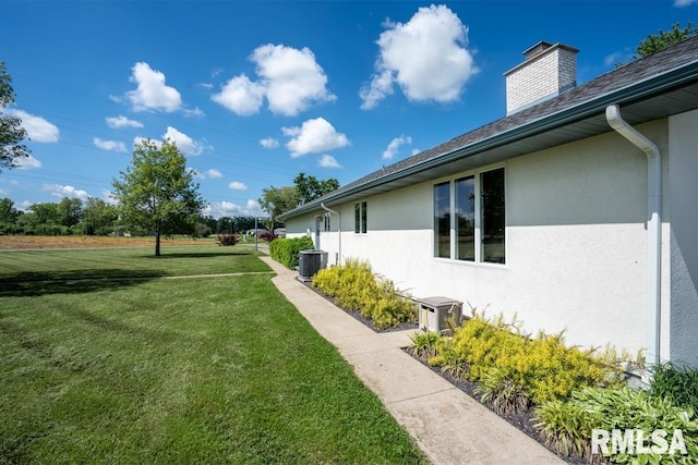 12 Old Marion Rd, West Frankfort, IL 62896 - view of side of home with stucco siding, a yard, a chimney, and cooling unit
