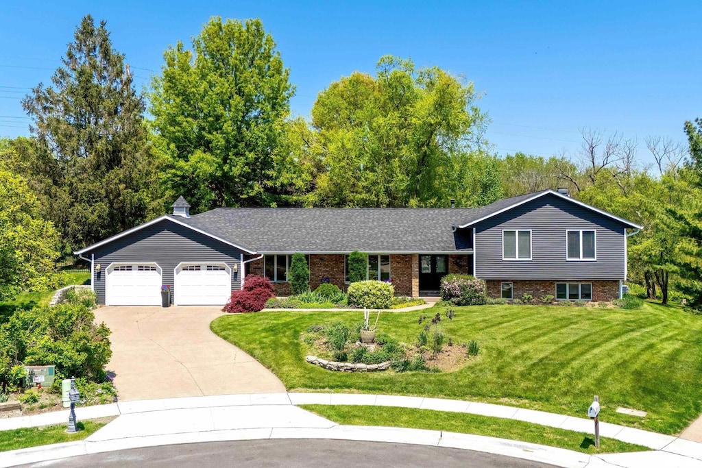 4105 Apple Valley Dr, Bettendorf, IA 52722 - tri-level home featuring concrete driveway, an attached garage, a front yard, and brick siding
