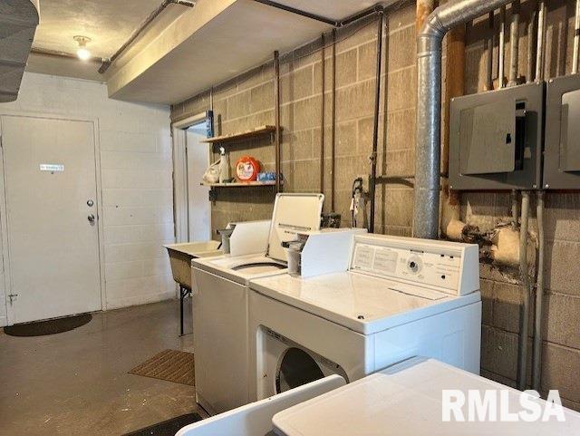 laundry area with washing machine and dryer, concrete block wall, and electric panel