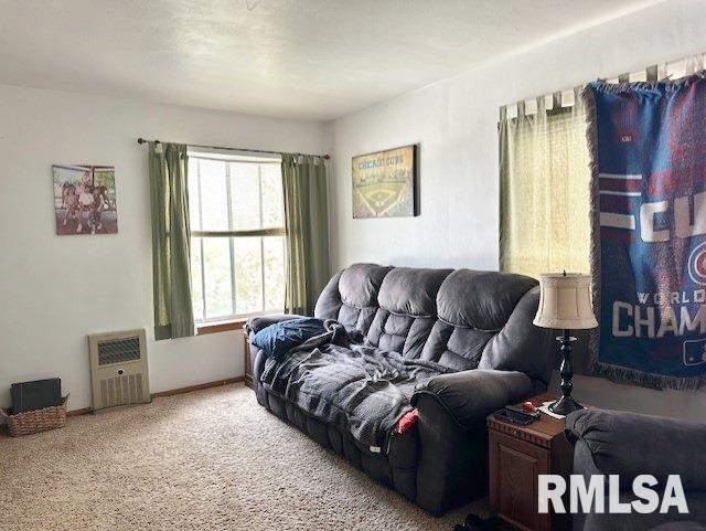 living area featuring carpet flooring, baseboards, and heating unit