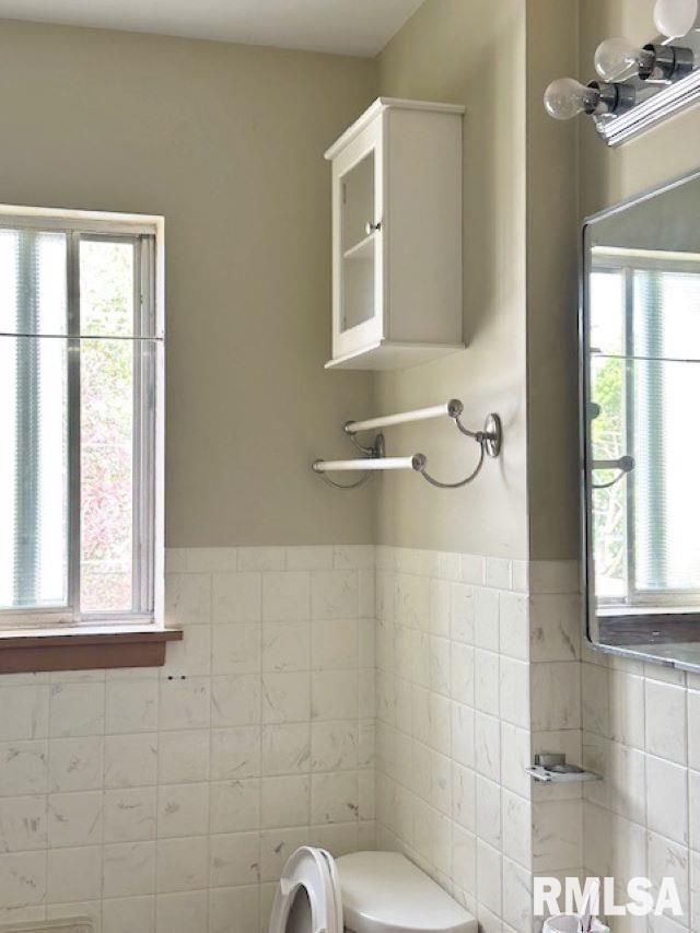 bathroom with toilet, tile walls, and wainscoting