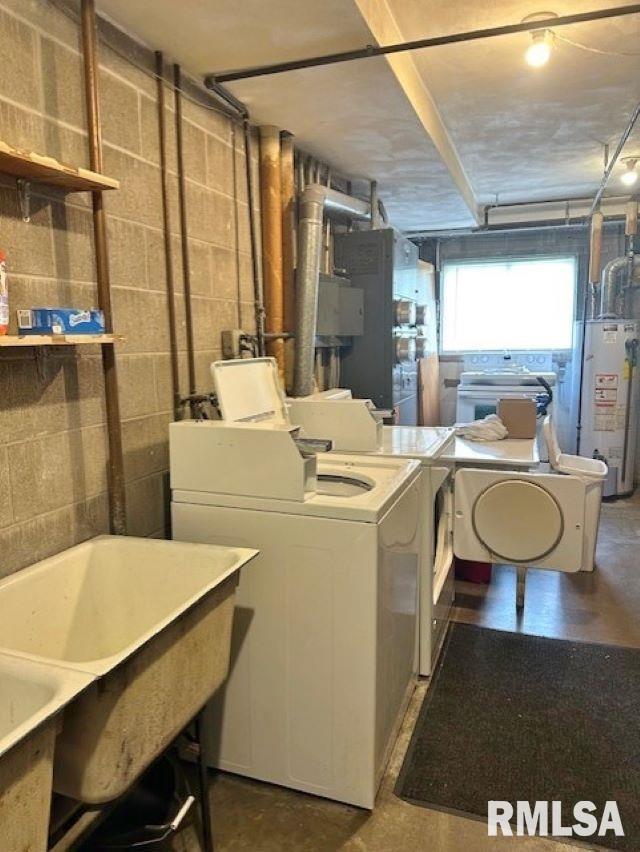 laundry room with independent washer and dryer, water heater, and concrete block wall