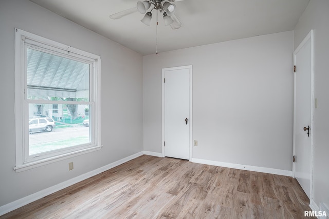 empty room featuring light wood-type flooring, a ceiling fan, and baseboards