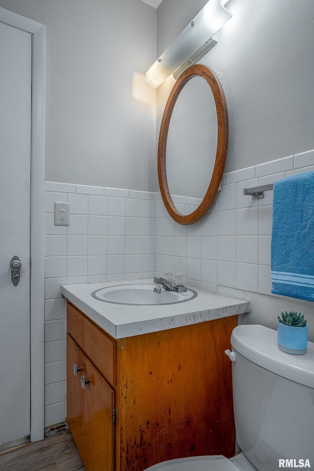 bathroom with tile walls, vanity, and toilet