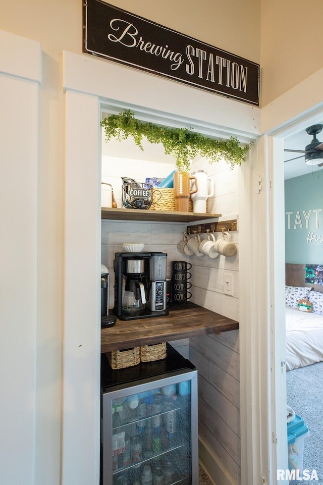 bar with beverage cooler, carpet floors, and a ceiling fan