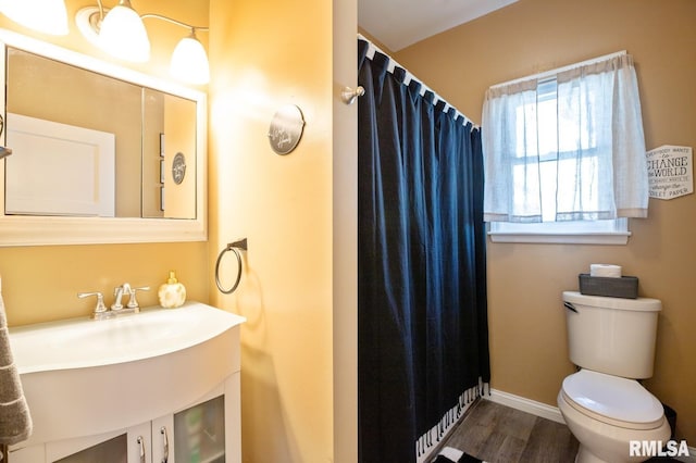full bathroom with toilet, wood finished floors, a shower with curtain, baseboards, and a sink
