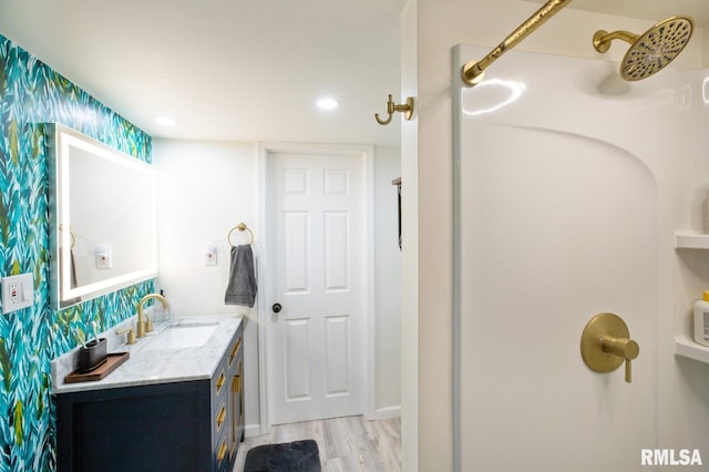 full bath with wood finished floors, vanity, and a shower