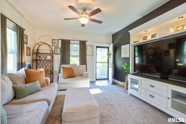 living area with light carpet, ceiling fan, and baseboards