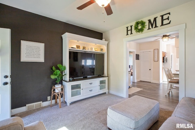 living area with a ceiling fan, baseboards, and wood finished floors