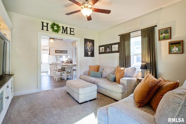carpeted living area featuring ceiling fan and baseboards