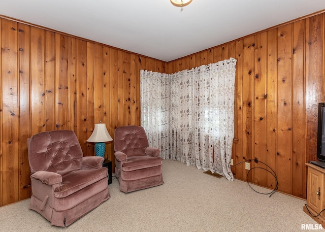living area featuring carpet and wooden walls
